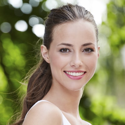 Woman smiling after receiving restorative dentistry and a take-home teeth whitening