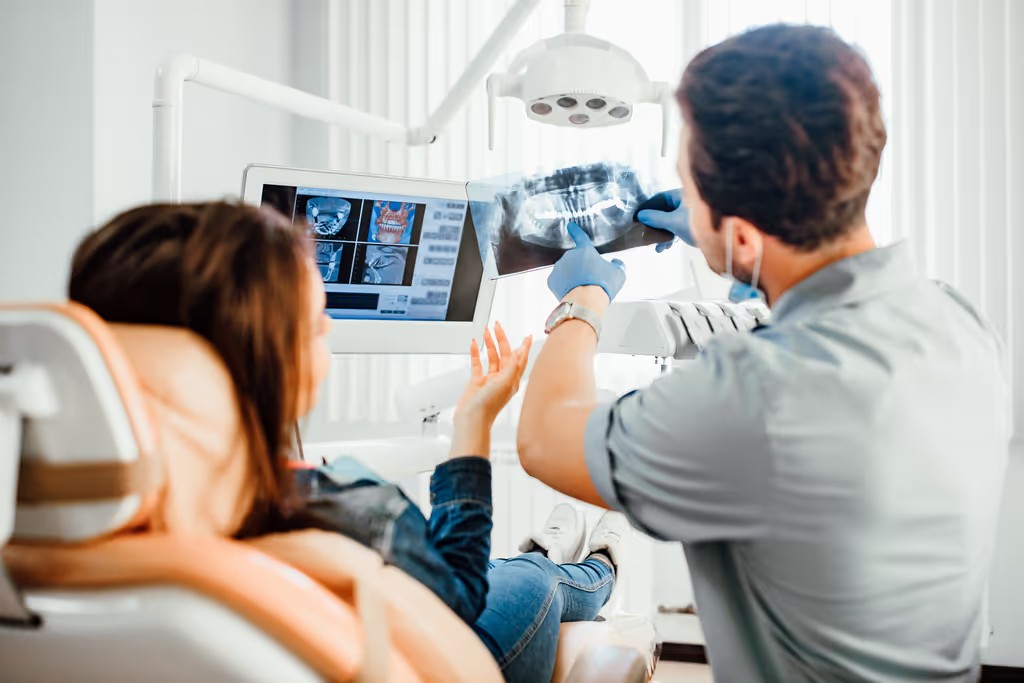 Dentist reviewing a panoramic X-ray with a visitor in the chair