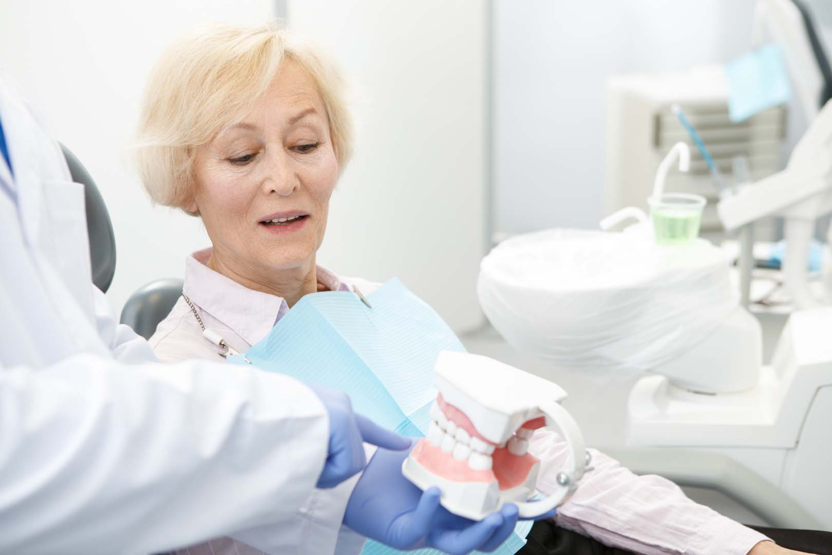 Patient and dentist discussing gum grafting procedure and dental model.